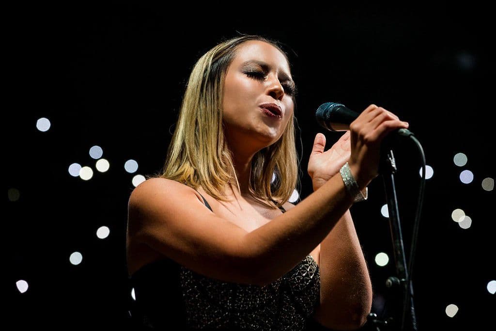 América Libertad cantando en un escenario a media luz